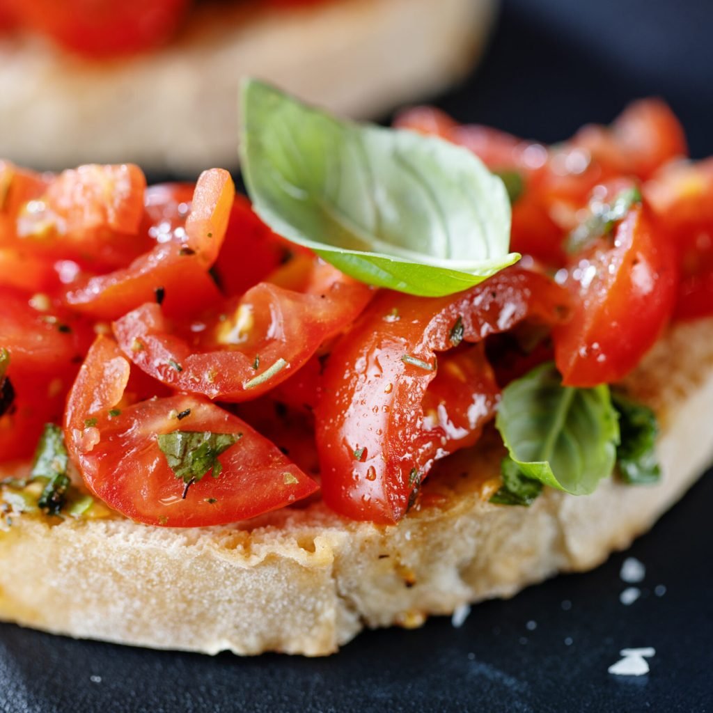 Tasty bruschetta with tomatoes and basil on bread. Closeup