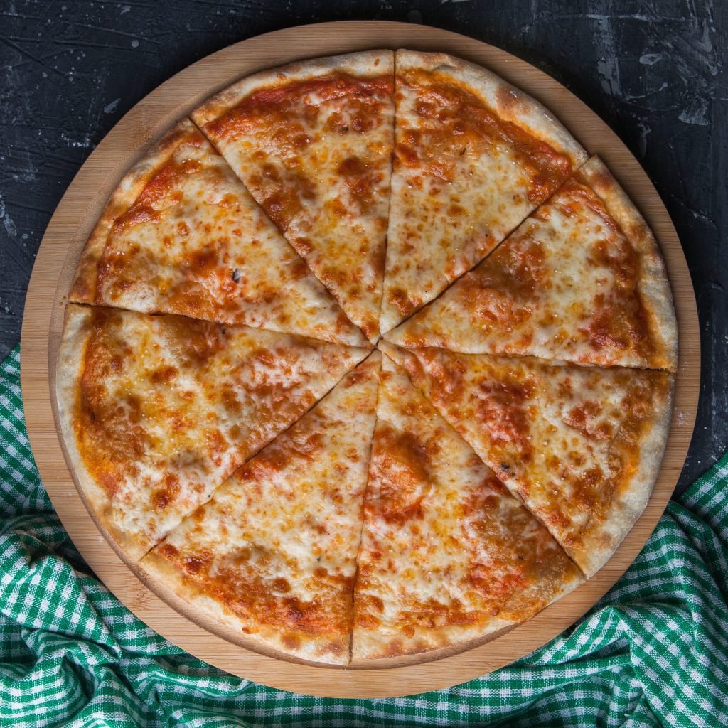 Side view closed pizza with checkered rag in round board on stone background